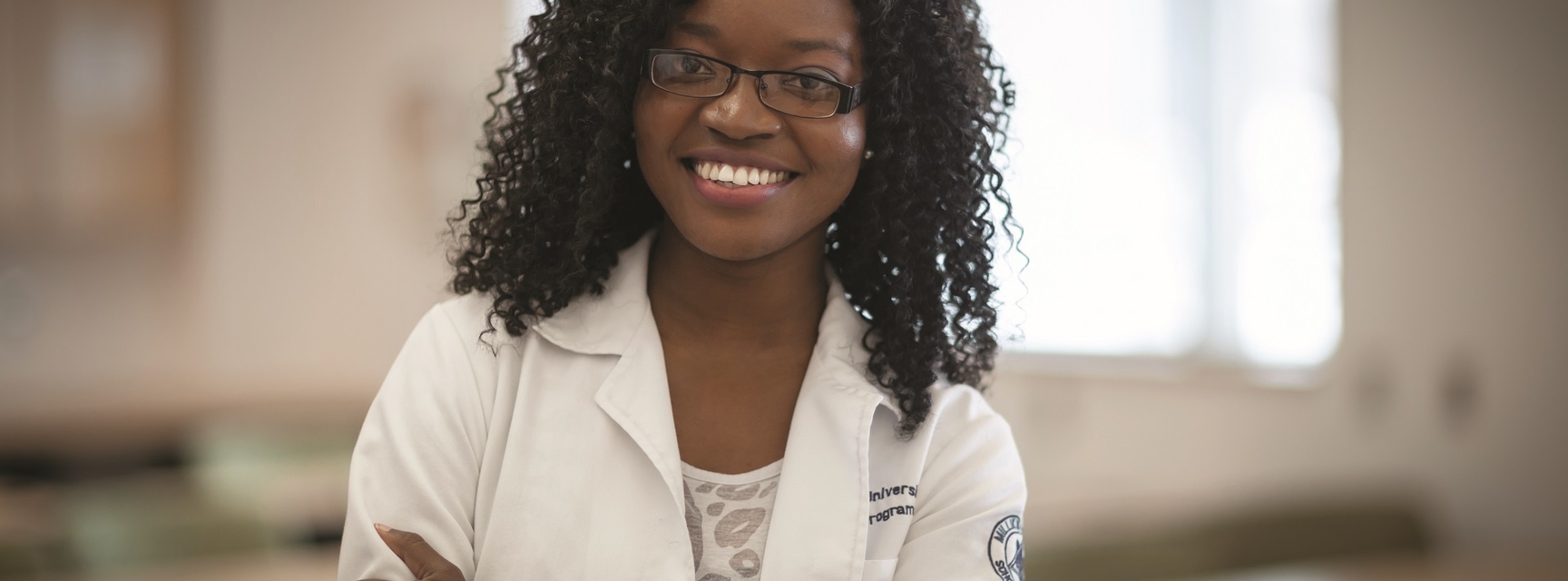 student in lab coat smiling