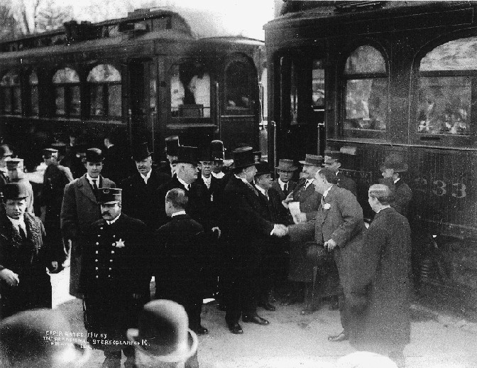 Image of President Taft shaking hands as he prepares to board the ITS train to Springfield on West Main St. in front of Millikin