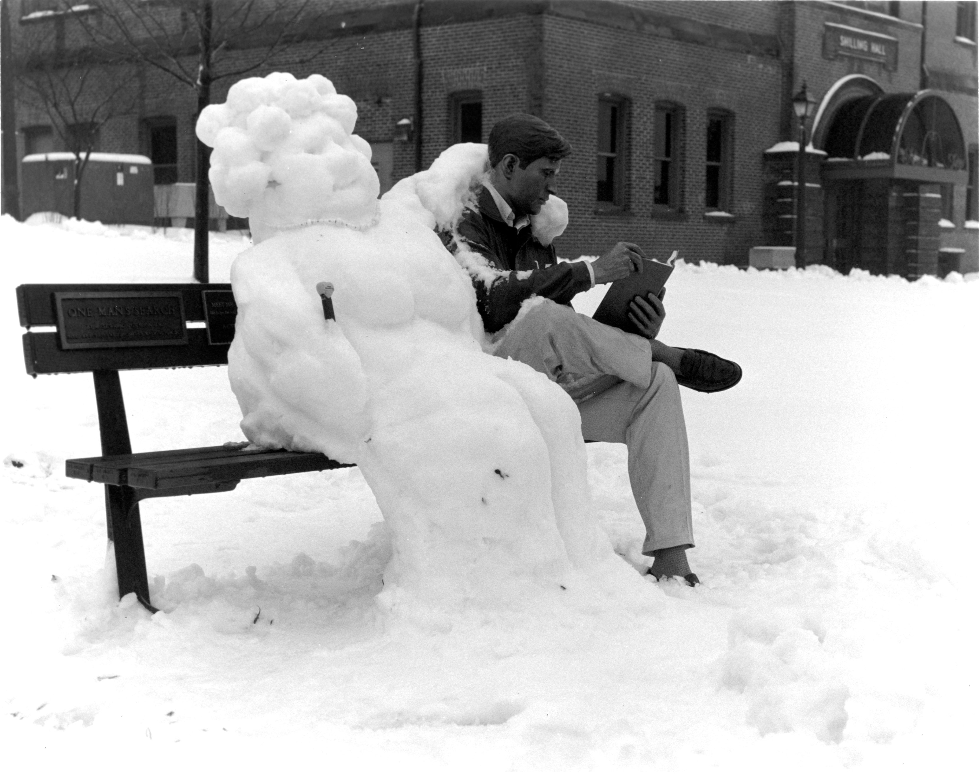 Black and white photo of a snow-woman with Mr. Bronze Man statue (1990s)