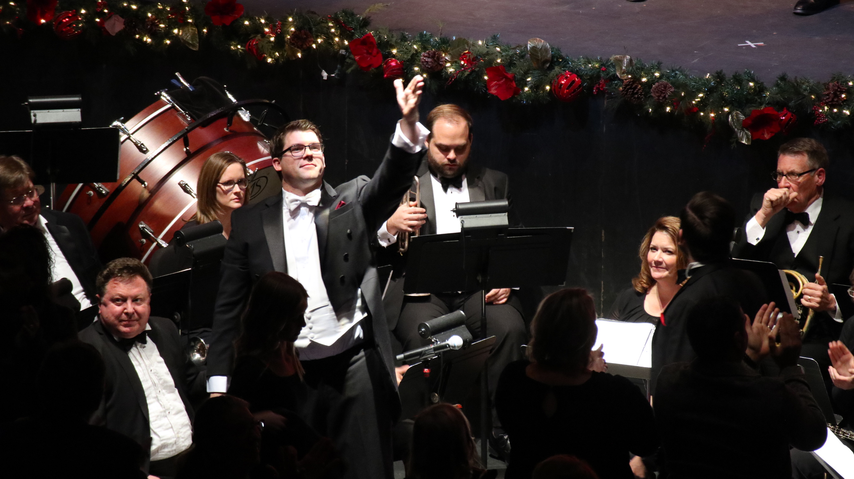 Director of Choirs Ben Hawkinson raises his hand to direct appalause at the choir in the balcony at Kirkland Fine Arts Center.