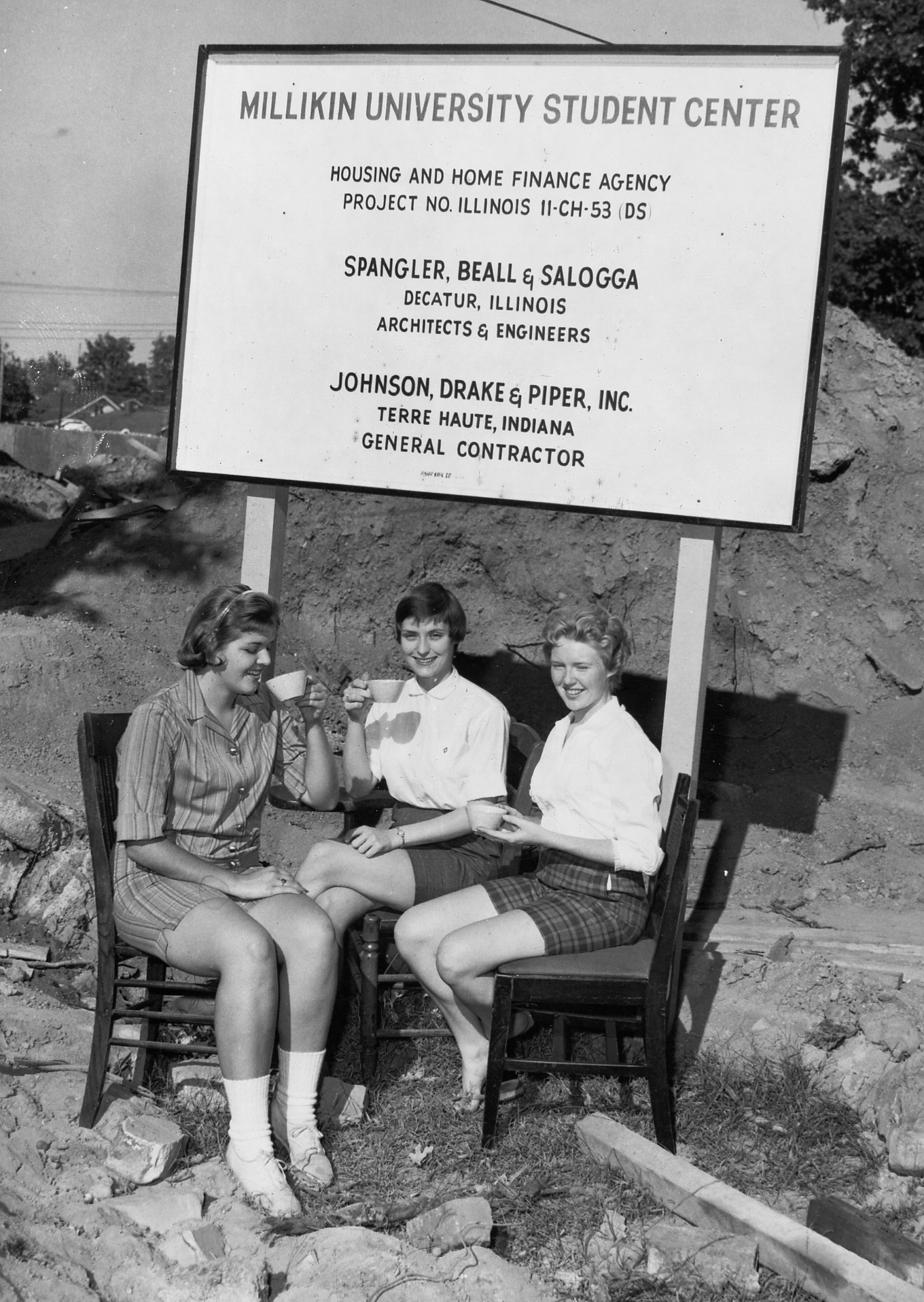 Black and white photo of Millikin co-eds having tea in front of the University Center construction site