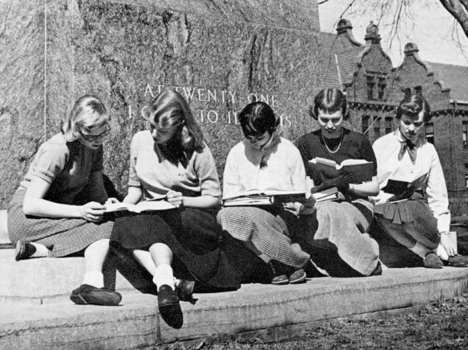 Black and white photo of Millikin co-eds studying on the base of the Lincoln statue
