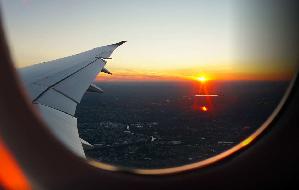 View looking out of airplane window at sunrise