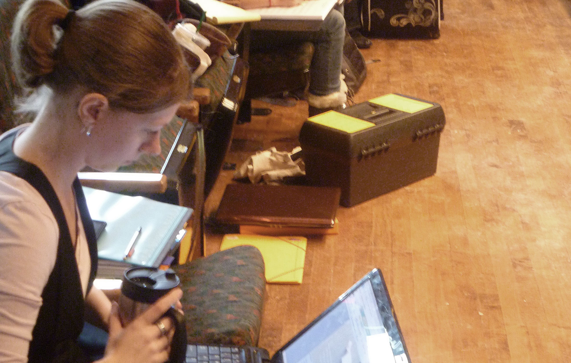 girl with coffee in hand working on laptop