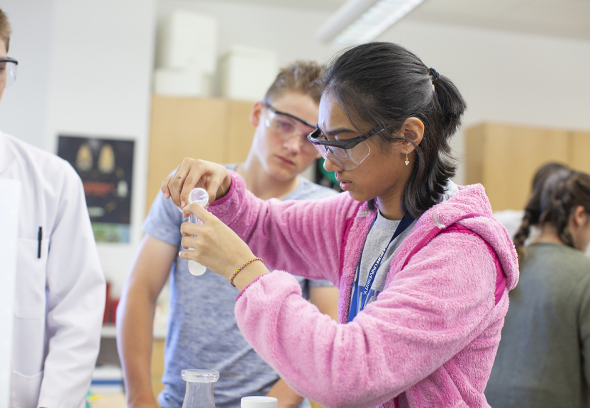 student measuring pouring fluid from a test tube