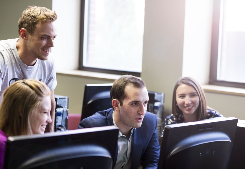 four students looking at a computer screen