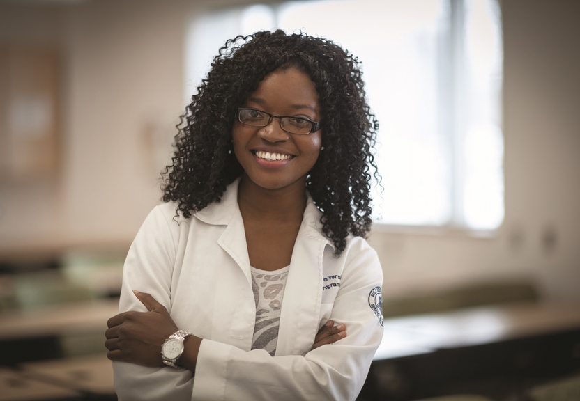 student in lab coat smiling