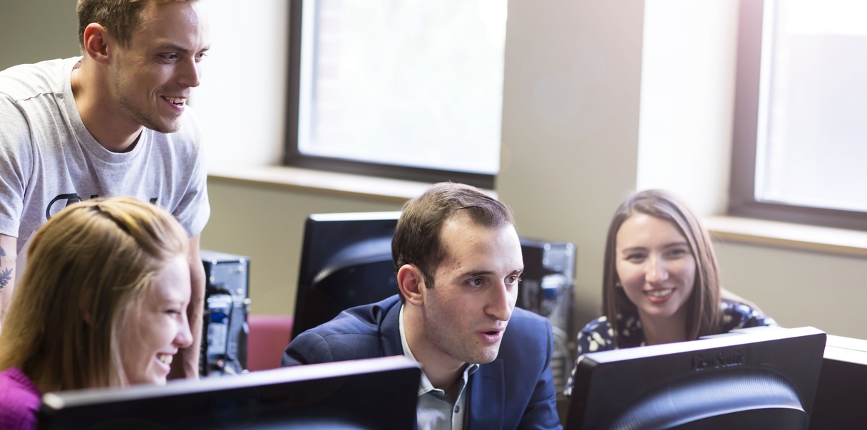 four students looking at a computer screen