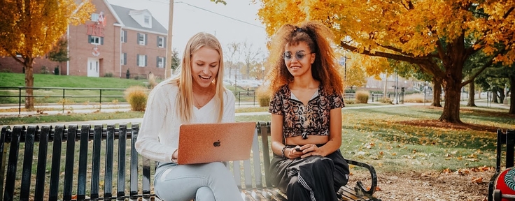 two students sitting looking at a laptop