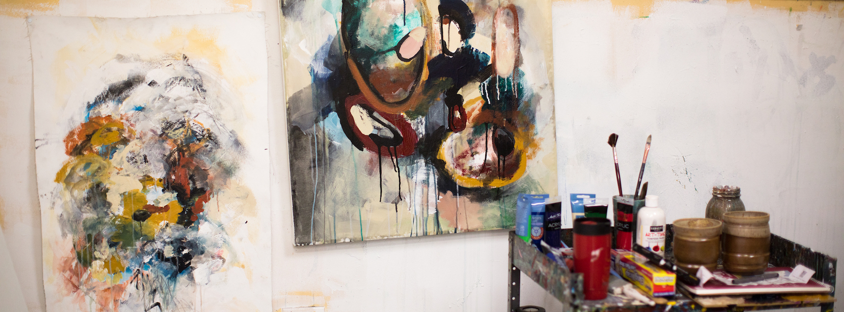 two paintings with art supplies on a cart 