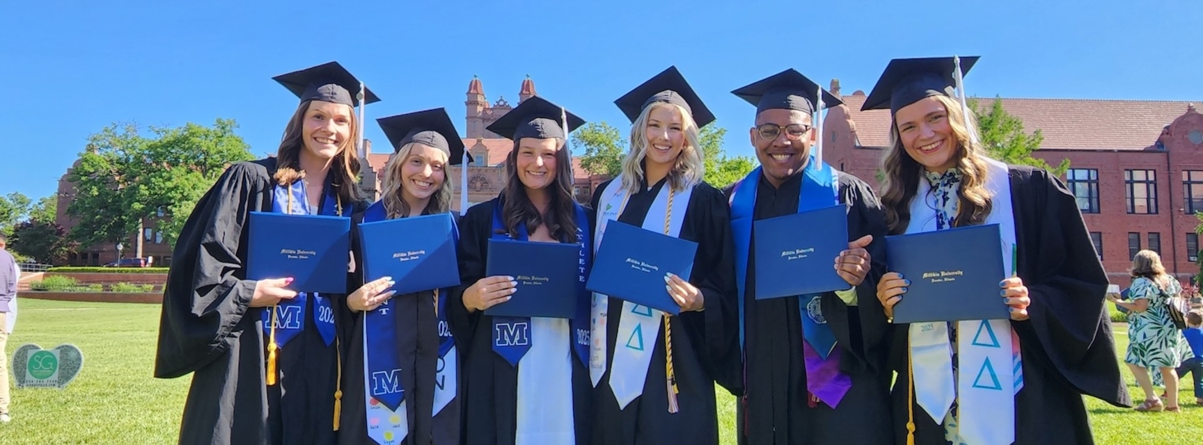 graduating students holding diplomas