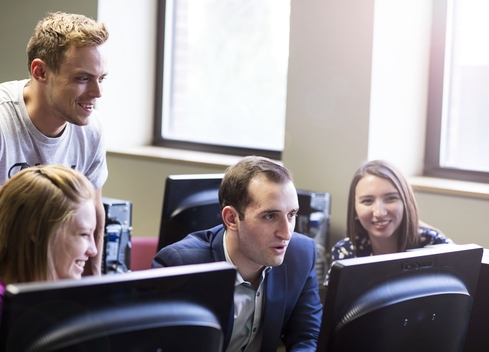 four students looking at a computer screen