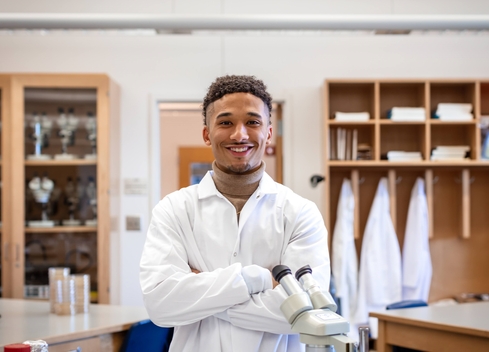 Male student in lab coat smiling at camera