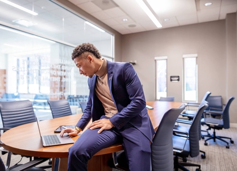 Student sitting on desk looking at laptop