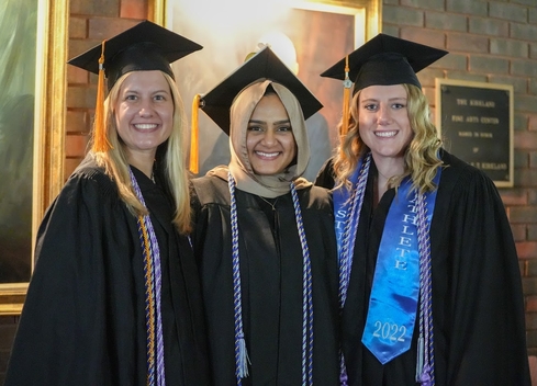 three graduating students standing together smiling