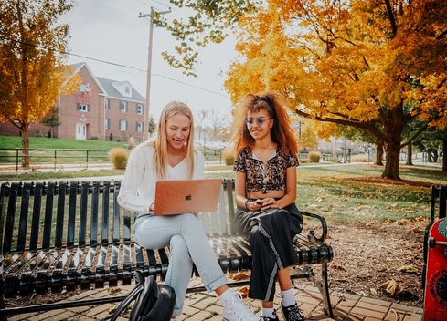 two students sitting looking at a laptop