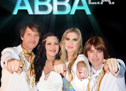 Dressed in all-white, the members of ABBA LA point directly at the camera.