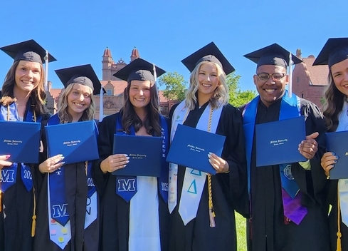 graduating students holding diplomas