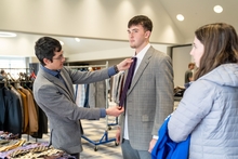 student getting fitted with tie at Dress to Impress event